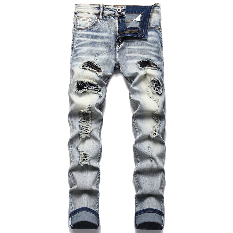 Cracked blue biker jeans: Pleated patch, ripped holes, distressed patchwork. Stretch denim, slim fit for streetwear style.